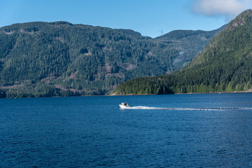Fototapeta na wymiar Small Speed Boat Moving across View of Alberni Inlet, Vancouver Island, B.C.
