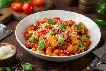 Spicy sausages marinara pasta in white bowl