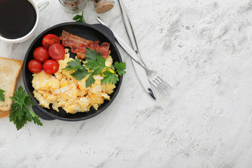 Frying pan with scrambled egg, bacon and tomatoes on white background