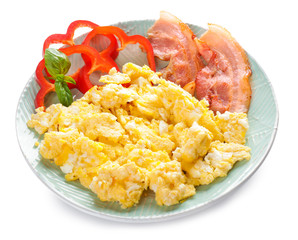 Plate with tasty scrambled eggs and bacon on white background