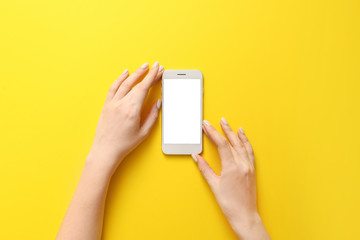 Female hands with mobile phone on color background