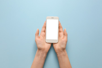 Female hands with mobile phone on color background