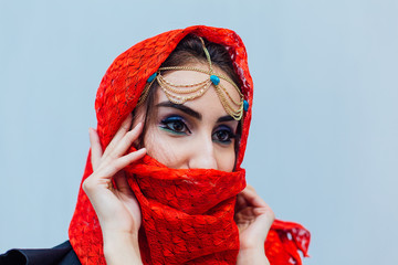 Beautiful eastern woman with makeup and jewelry wearing headscarf.