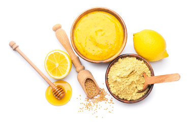 Bowl of tasty honey mustard sauce with ingredients on white background