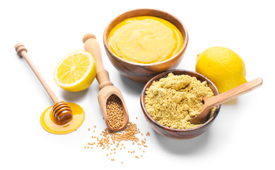 Bowl of tasty honey mustard sauce with ingredients on white background