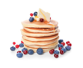 Tasty pancakes with honey, butter and berries on white background