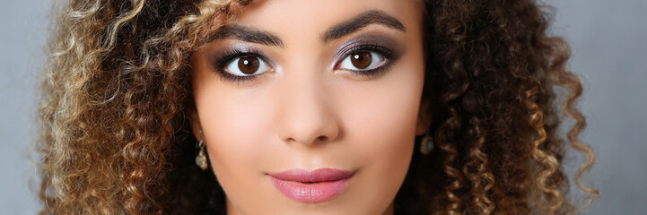 Naklejka premium A beautiful black woman with a large face portrait. On a gray background a smiling beauty fashion style curly hair with white locks eye view of the camera