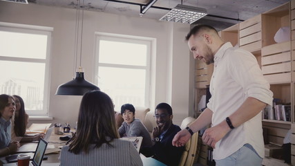 Camera follows male legs on hoverboard in modern office. Young businessman using segway to move indoors, meet team 4K. - Powered by Adobe