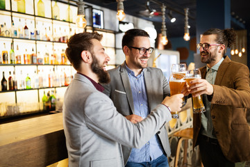 Happy young business men talking and drinking beer in a pub