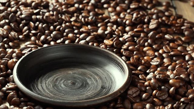 Black coffee beans slowly fall into the bowl 