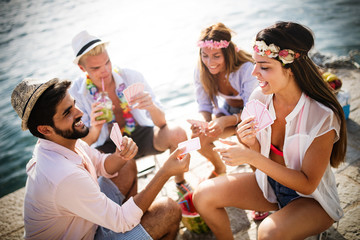 Group of happy friends playing carts and having fun