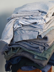 Warm knitwear stacked on a bench after washing. Store. Blue gray white tones. Gray background.