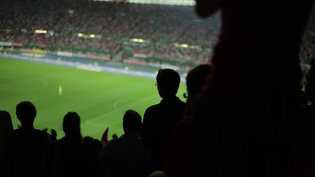 silhouettes of many soccer fans in football stadium watching match clapping hands to support teams, with audio