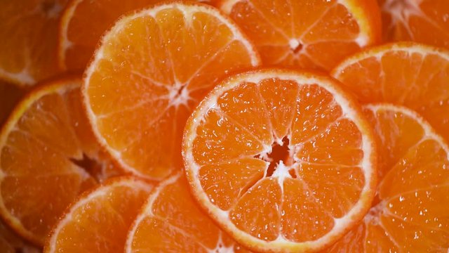 Fresh sliced orange fruit texture on rotating background. Top view. Citrus fruits. Vegan and raw food concept. Juicy oranges background