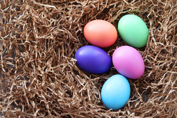 Easter multicolored eggs lie in the hay the decorative paper. selective focus. Easter still life