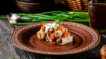 Ukrainian cuisine. Stuffed cabbage rolls with sour cream. Serving dishes in a clay plate. Sour cream is poured on top. background image, copy space text