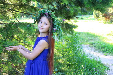 beautiful girl in a blue dress with a bouquet of daisies and a wreath of wildflowers in the summer...