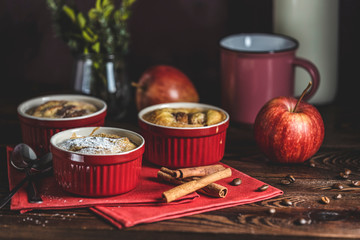 Romantic breakfast or supper with coffee. Apple pie in ceramic baking molds ramekin on dark wooden table. Close up, shallow depth of the field.