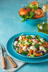 Blue plate of fresh superfoods healthy salad with red onion, tomatoes, doucette (lambs lettuce, corn salad, field salad) and feta cheese. Light blue surface