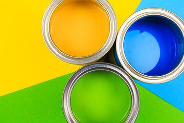 Metal paint cans and paint brushes on multicolor background. Top view. Copy space. - Image