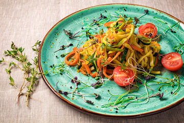 Vegetable pasta with carrot and zucchini. Served on a ceramic plate.