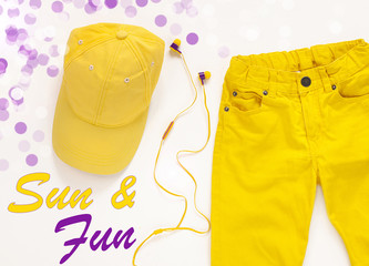 Yellow flatlay jeans, baseball cap and headphones summer background card,top view.Sun and fun...