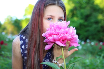 Naklejka premium Flowering peonies. Beautiful Caucasian girl with long brunette hair in a botanical garden where bright pink and white peonies bloom. Nature and relaxation. Botanical Garden. Flowers