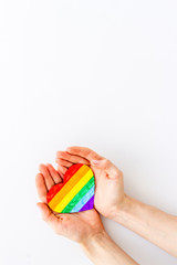 LGBT symbol. Rainbow heart in hands on white background top-down copy space