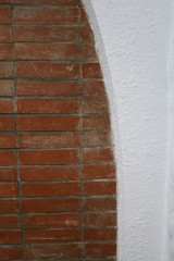 Curved wall, white wall and exposed red bricks