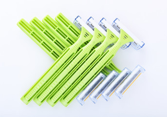 Disposable green plastic razor on a white background.Safe shaving with a sharp razor of female skin. Hair removal from the legs and face. Body care and beauty of a woman.