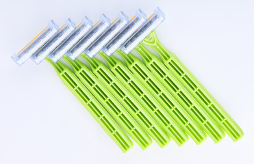 Disposable green plastic razor on a white background.Safe shaving with a sharp razor of female skin. Hair removal from the legs and face. Body care and beauty of a woman.