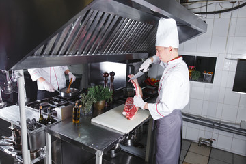 cook cooks beef steak in the restaurant kitchen