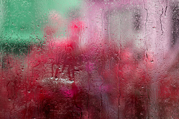 Wet glass with colorful blurs