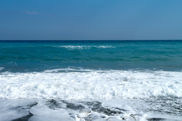 Aquamarine sea, white foamy waves and blue sky