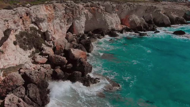 aerial drone view of beautiful waves crashing at rocky cliff with splashing and white foam, cyprus landscape Aya Napa