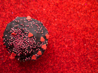 Cupcake decorated with a hearts on red background