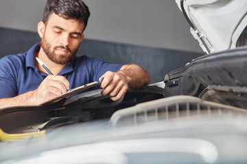 Mechanic in auto repair shop with checklist
