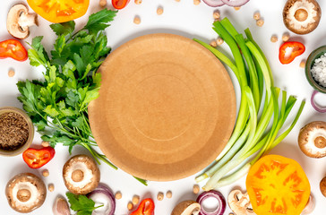 Fresh vegetables, chickpeas and herbs around blank paper plate on a white background, top view,...