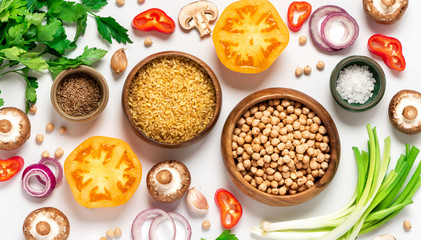 Bulgur, chickpeas, tomatoes, mushrooms, peppers, onions, spices and herbs on a white background, top view. Vegetarian and vegan food, Mediterranean cuisine ingredients. Food background