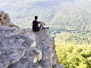 guy sits on a rock near a cliff © ASHarchenko