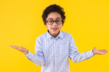Curly smart clever african american boy in blue shirt and round glasses on yellow background. Black...