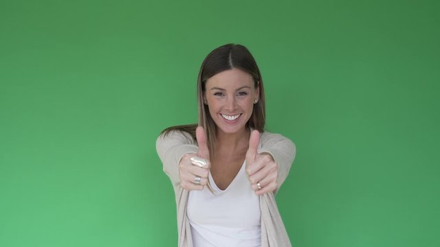 Portrait of cheerful woman showing thumbs up on green background, isolated