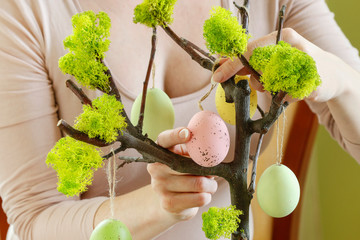 Woman shows how to make Easter decoration in tree shape with hanging eggs