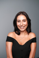 Naklejka premium A large portrait of a middle-aged woman (30-35 years old) with dark hair and brown eyes in a black dress on a light background.