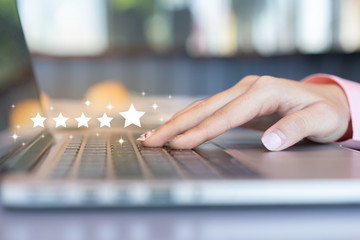 close up on customer woman hand pressing on laptop keyboard with  five star rating feedback icon...