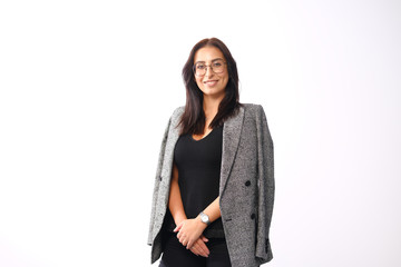 Portrait of a smiling mid-aged business woman with dark hair and brown eyes in glasses and a jacket against a light wall