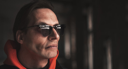 man in sunglasses looks away, closeup on a dark background