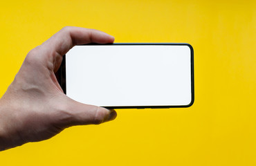 The man's hand shows a smartphone with a white screen in the horizontal position