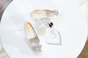 White women’s shoes and silver women’s jewelry. Bottle of perfume. Wedding fashion and decor, top view