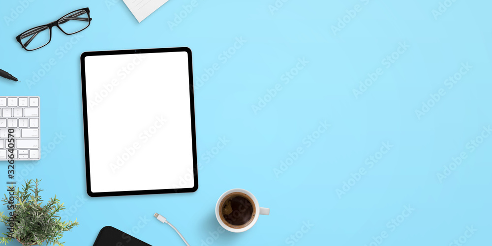 Sticker tablet mockup on blue work desk with plenty of space for text. top view, flat lay scene with up of c